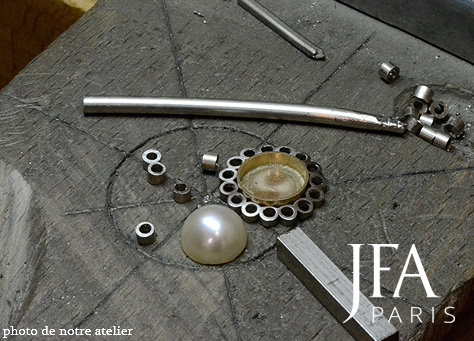 Pendentif en platine et or jaune serti en son centre d´une perle et d´un double entourage de diamants articulés.